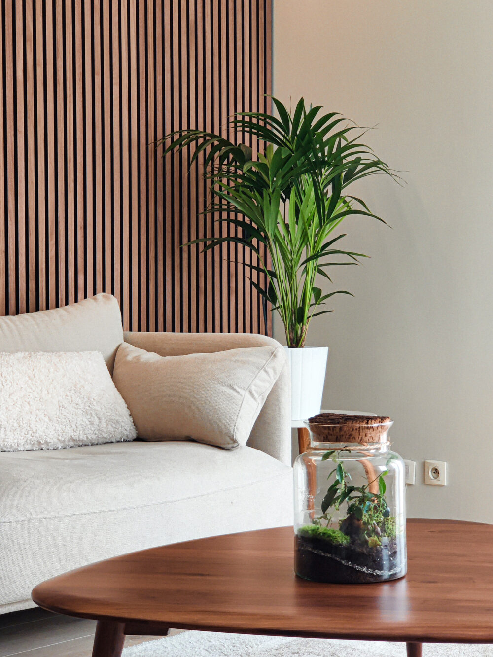 Zoom sur un canapé contemporain avec un mur en claustra bois et table basse scandinave