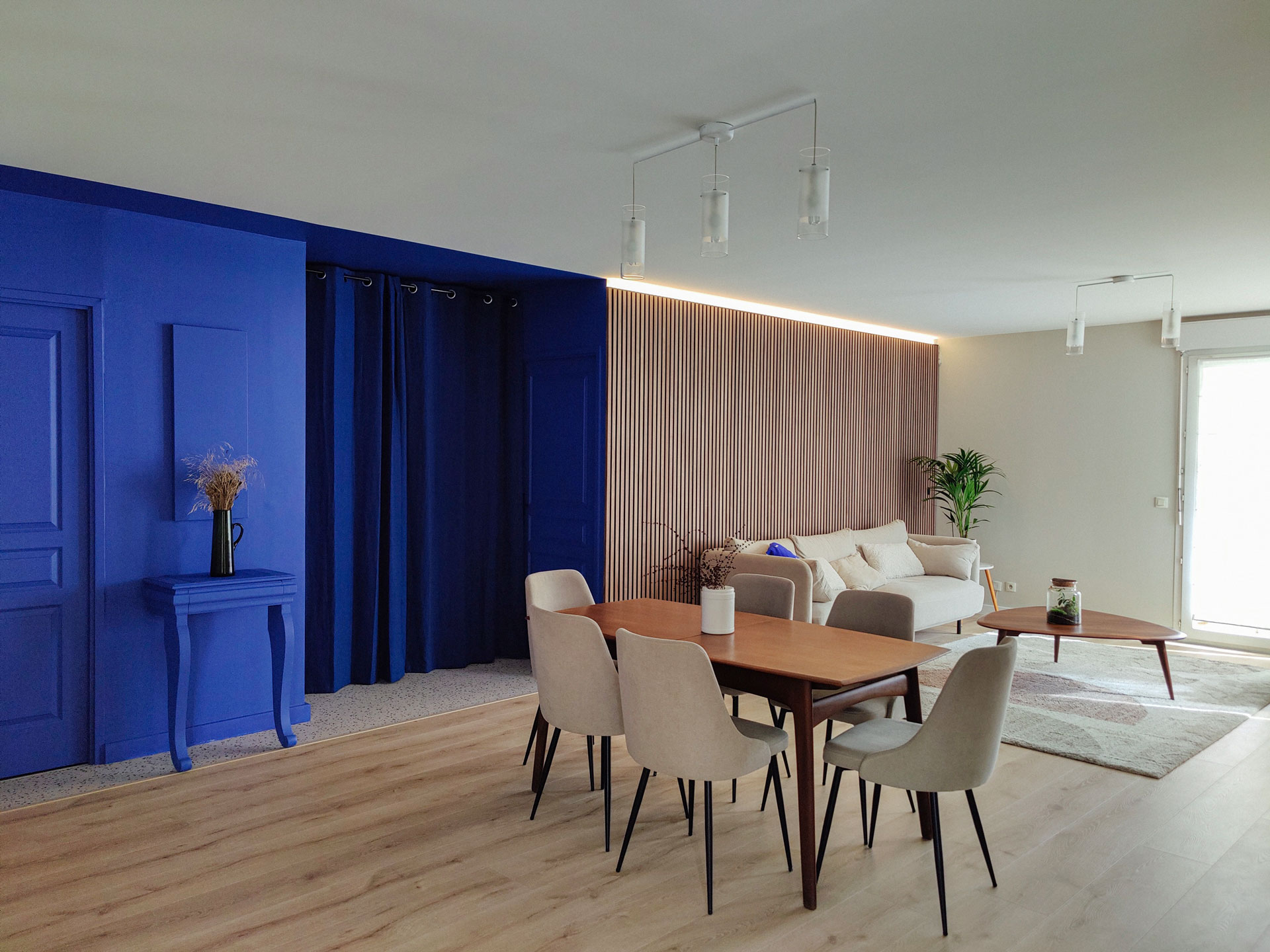 Rénovation d'un salon contemporain chaleureux avec mur en claustra bois entrée monochrome bleu klein