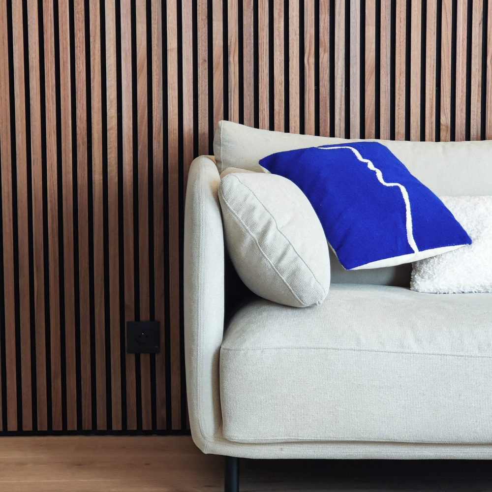 Zoom sur un canapé contemporain avec un mur en claustra bois